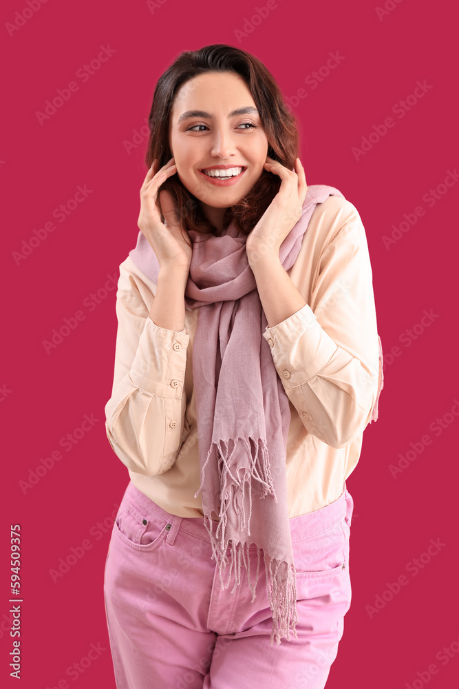 Stylish young woman in scarf on pink background