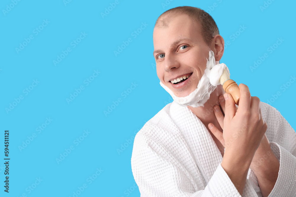 Young man shaving against light blue background