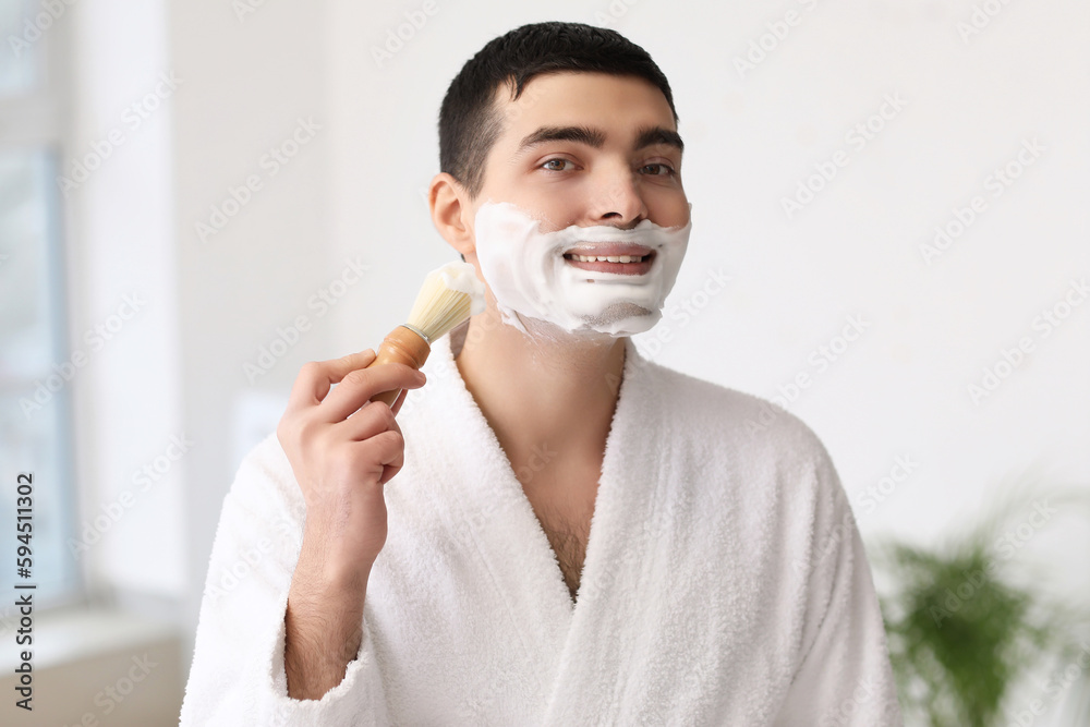 Young man shaving in bathroom