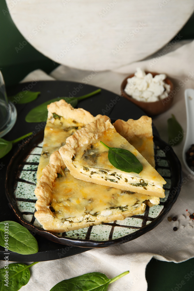 Plate with pieces of delicious quiche on green background