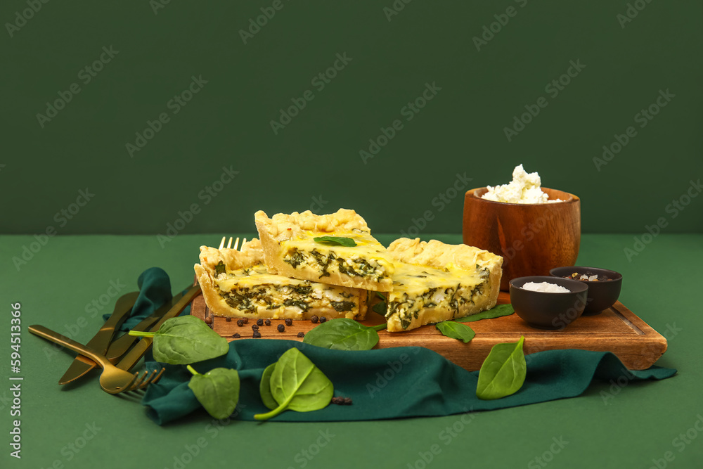 Board with pieces of delicious quiche on green background