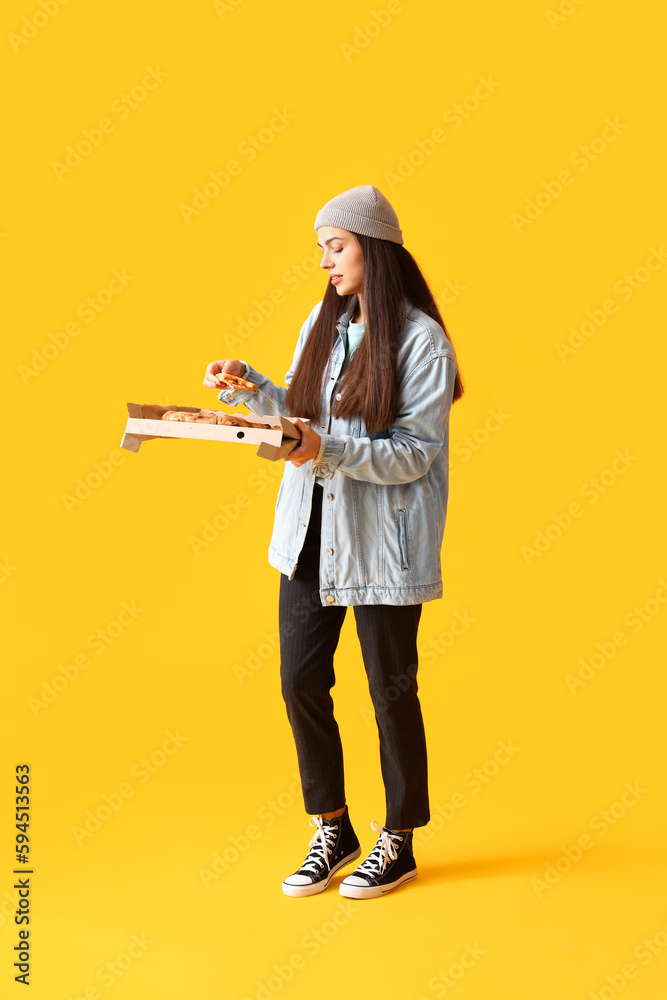 Young woman with box of tasty pizza on yellow background