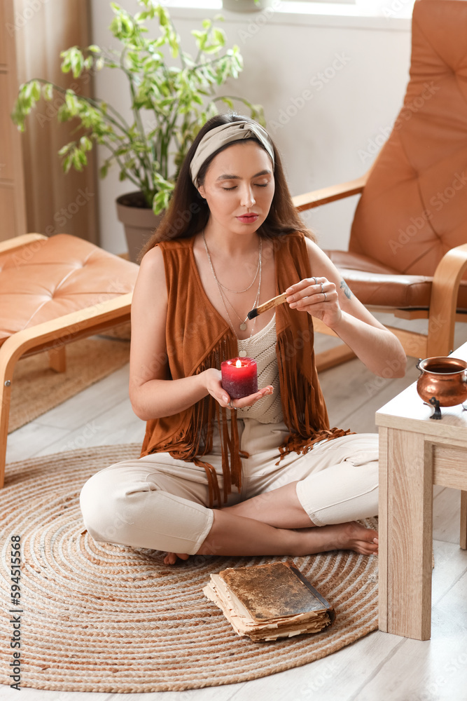 Young witch with candle and palo santo cleansing space at home