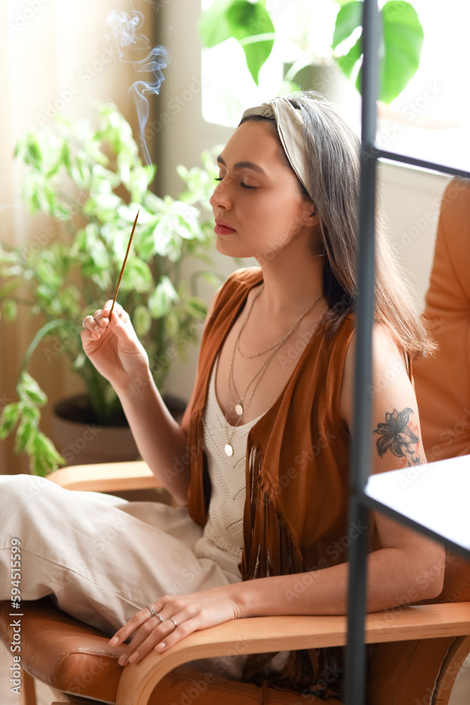 Young woman with incense cleansing space at home