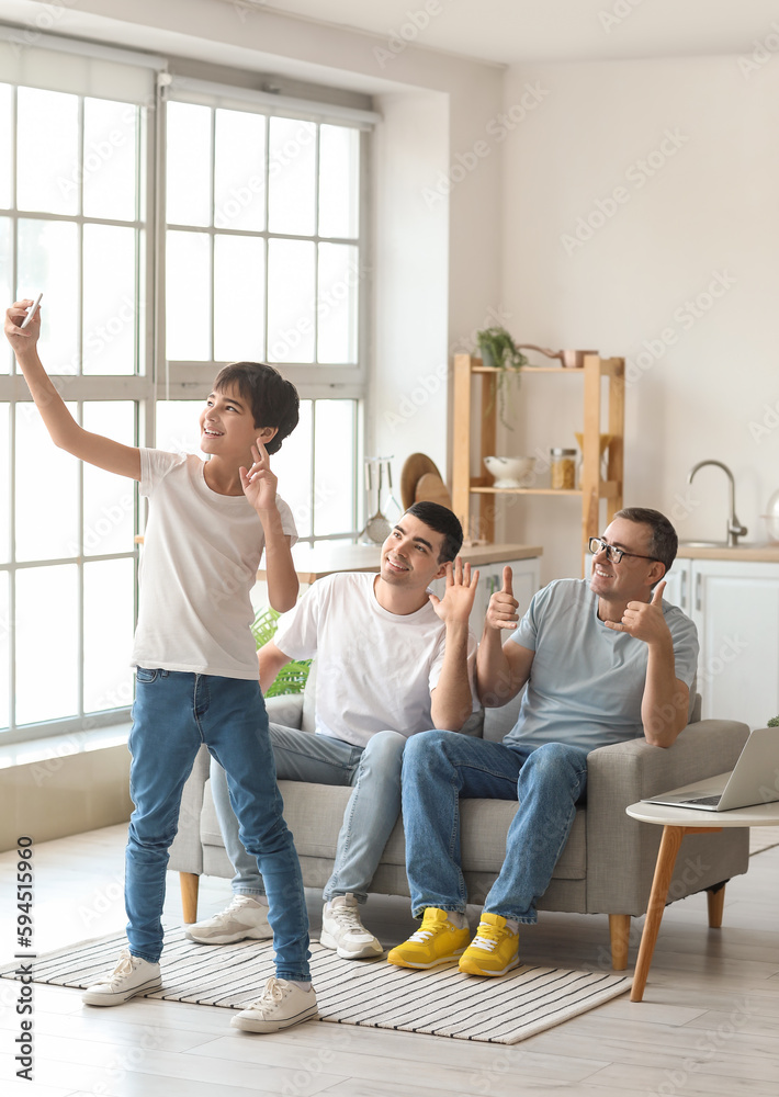 Happy little boy with his dad and grandfather taking selfie at home