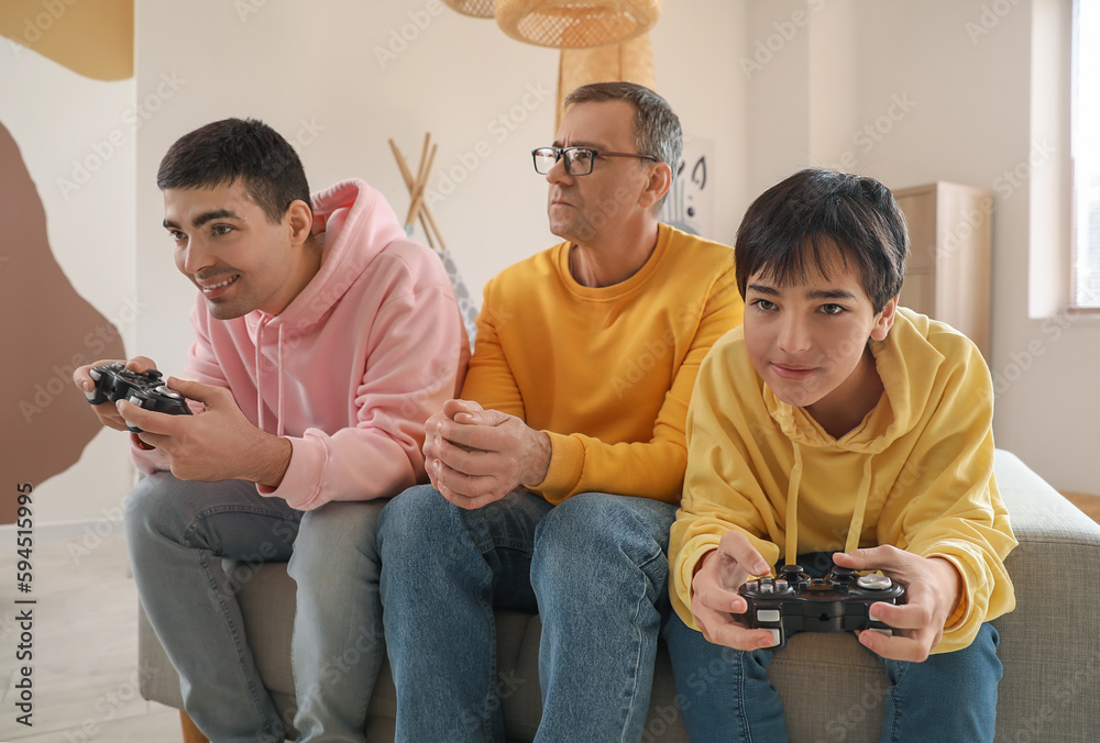 Happy little boy with his dad and grandfather playing video game at home