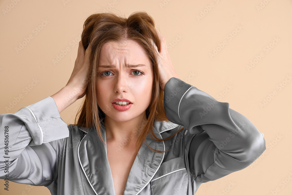 Worried young woman with hair loss problem on beige background