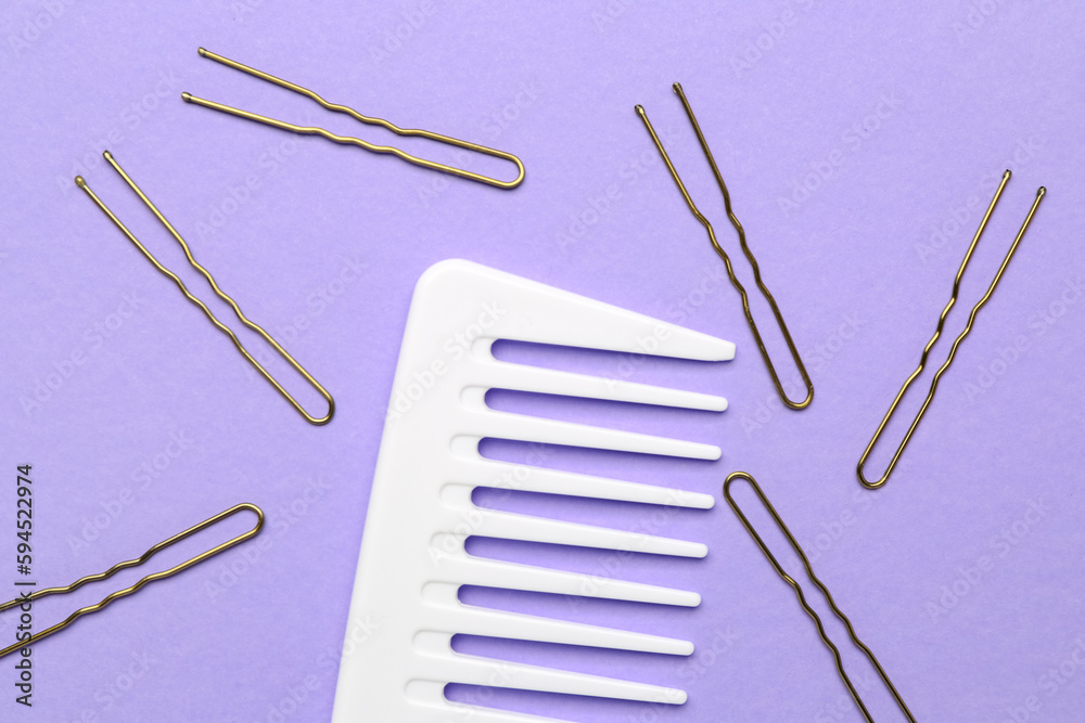 Comb with hairpins on violet background, closeup