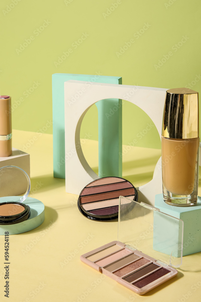 Decorative cosmetics with podiums on table near green wall