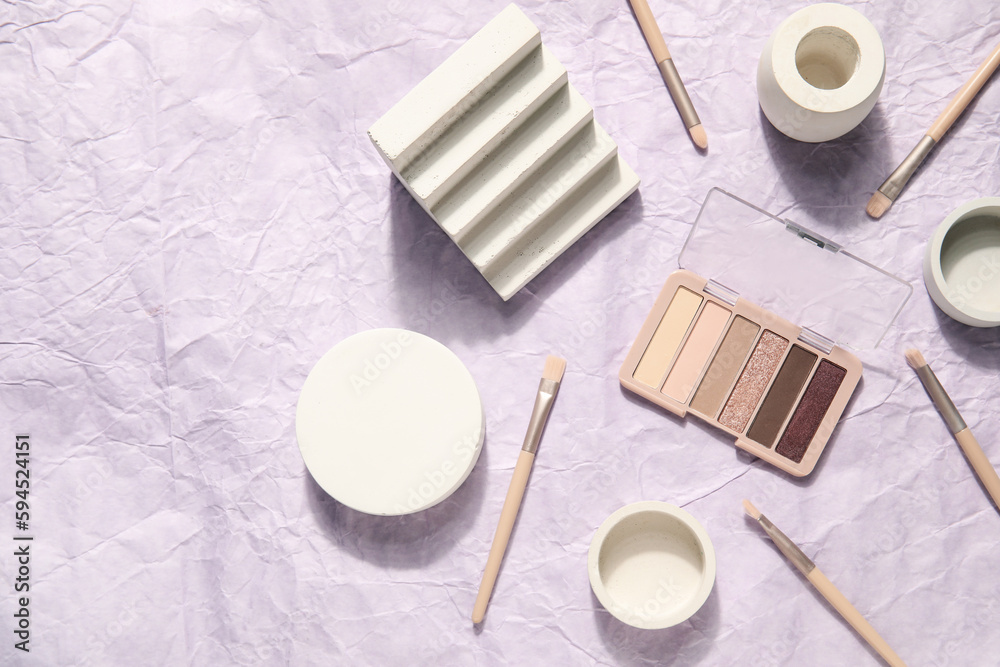 Eyeshadows with brushes and podiums on crumpled paper background