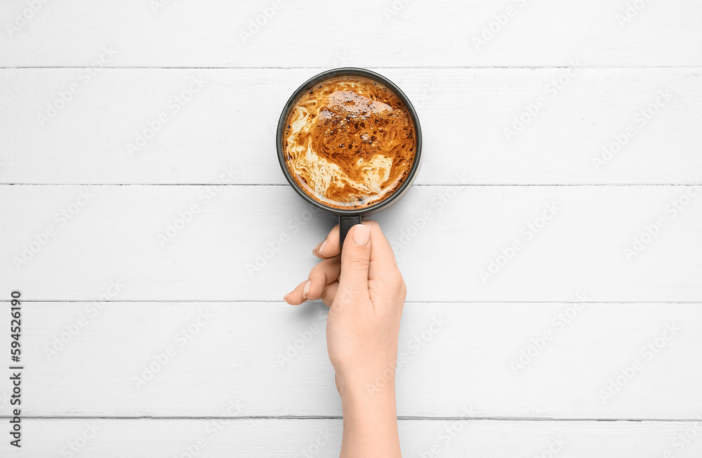 Woman with cup of coffee on white wooden background