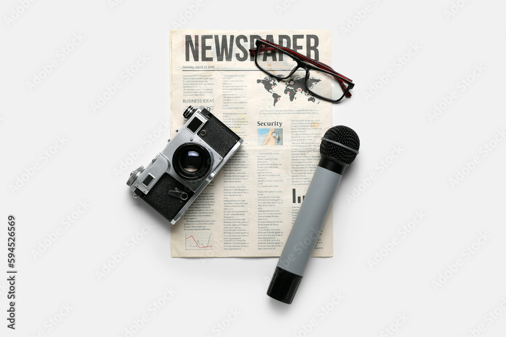 Newspaper with microphone, photo camera and eyeglasses on white background