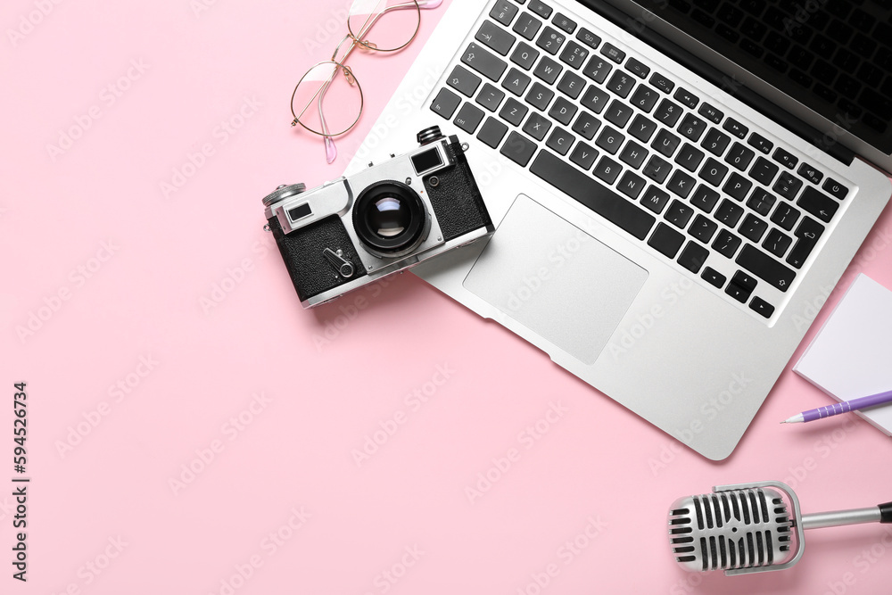 Laptop with photo camera, eyeglasses and microphone on pink background