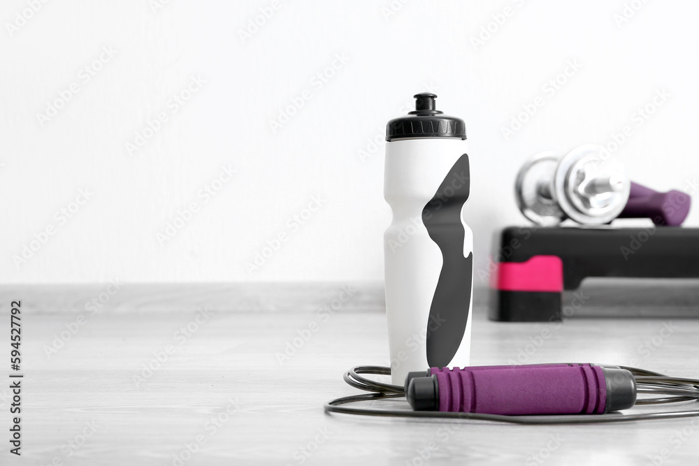 Sports water bottle with skipping rope in gym, closeup