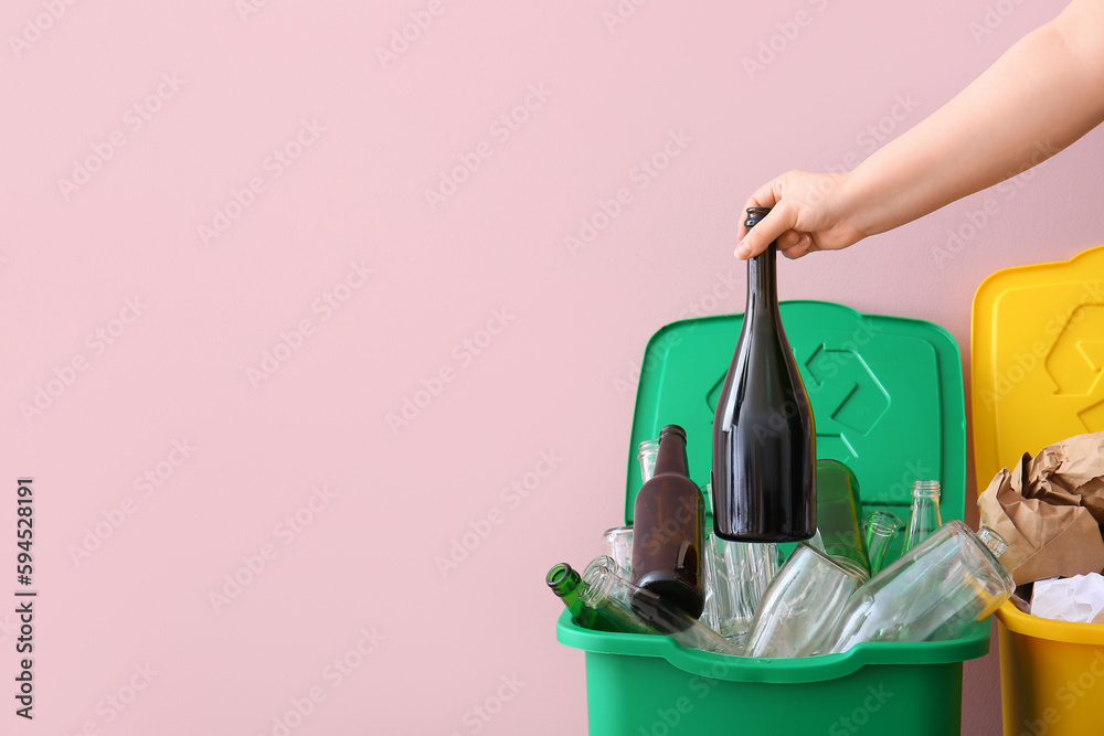 Woman throwing garbage into trash bin near pink wall. Recycling concept