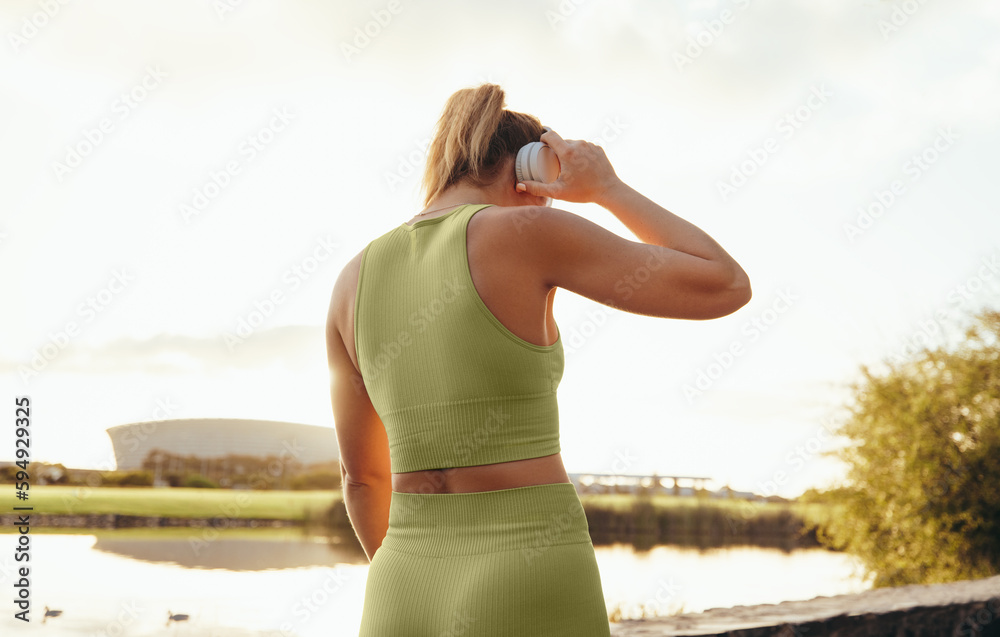 Rearview of a sports woman listening to music on headphones outdoors