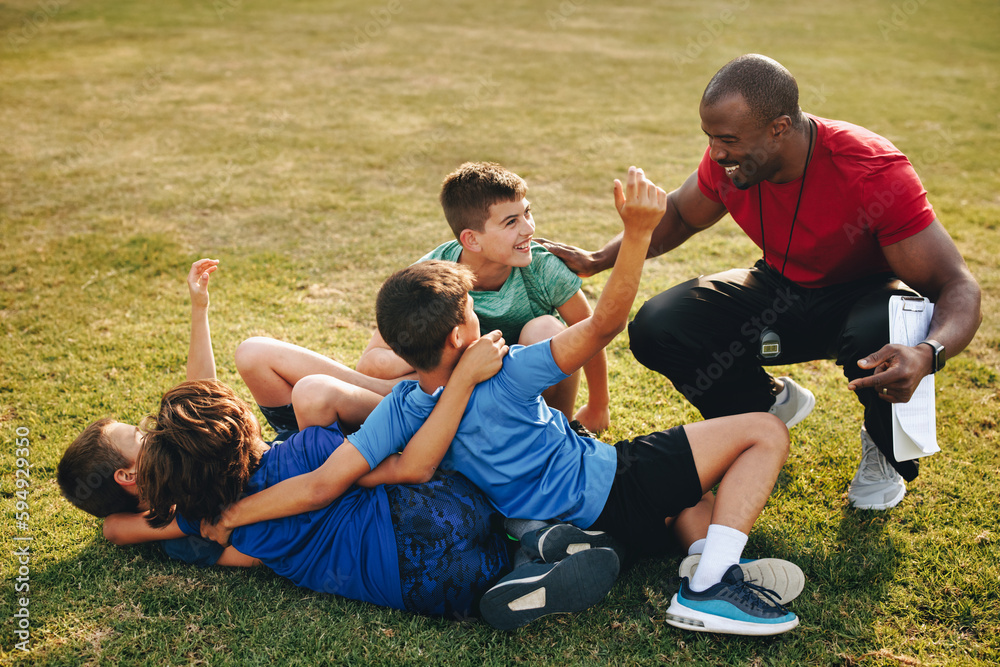 Male coach raining elementary school kids in a sports ground