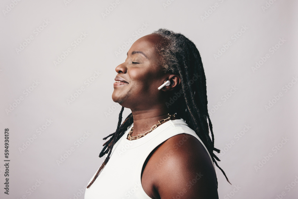 Cheerful mature woman listening to some music on bluetooth earbuds