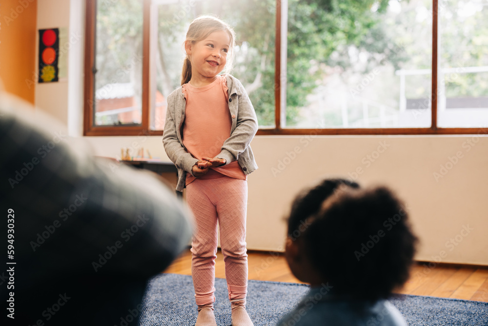 Shy little girl standing in front of her class to do an oral presentation