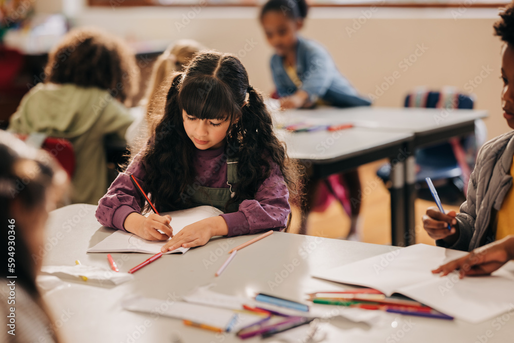 Creative young girl drawing with a pencil in a class