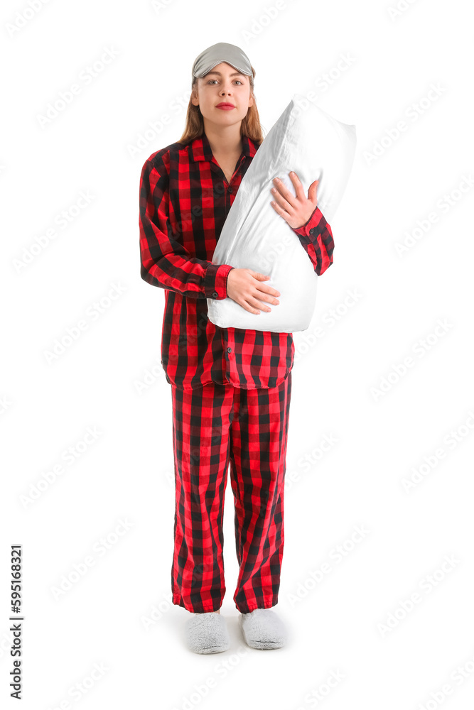 Young woman in checkered pajamas with pillow on white background