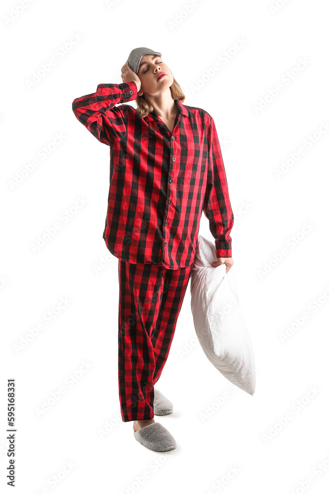 Young woman in checkered pajamas with pillow on white background