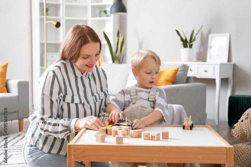 Mother and her little son playing with wooden toys at home