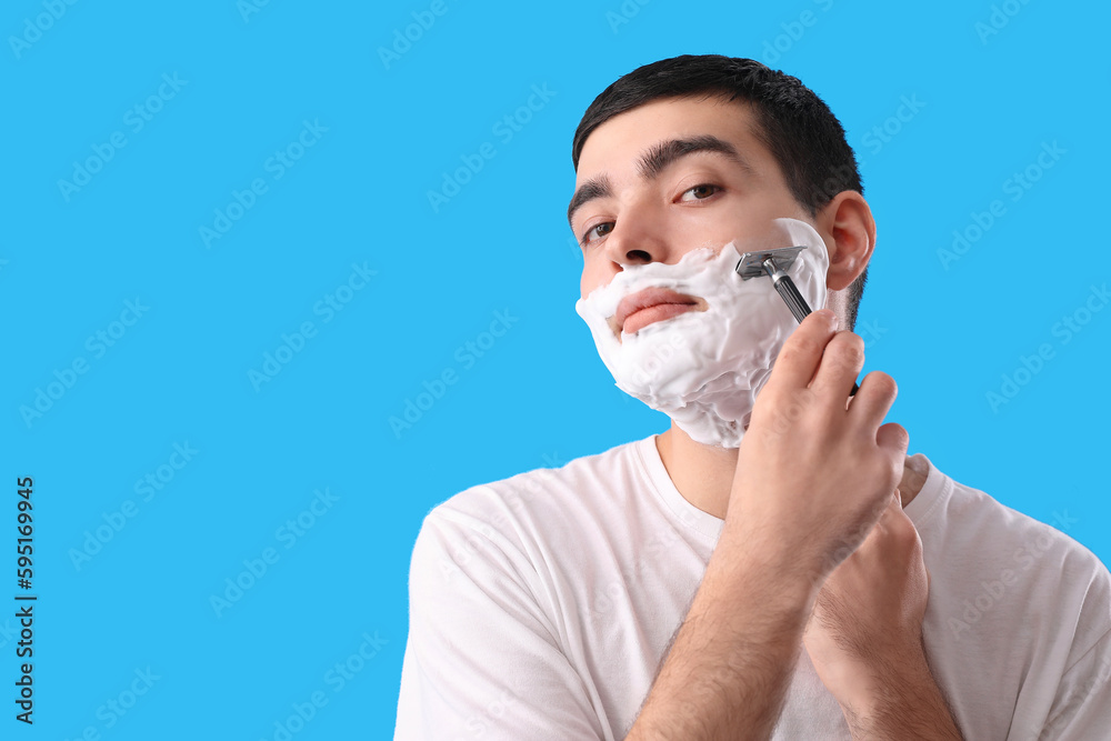 Young man shaving against light blue background