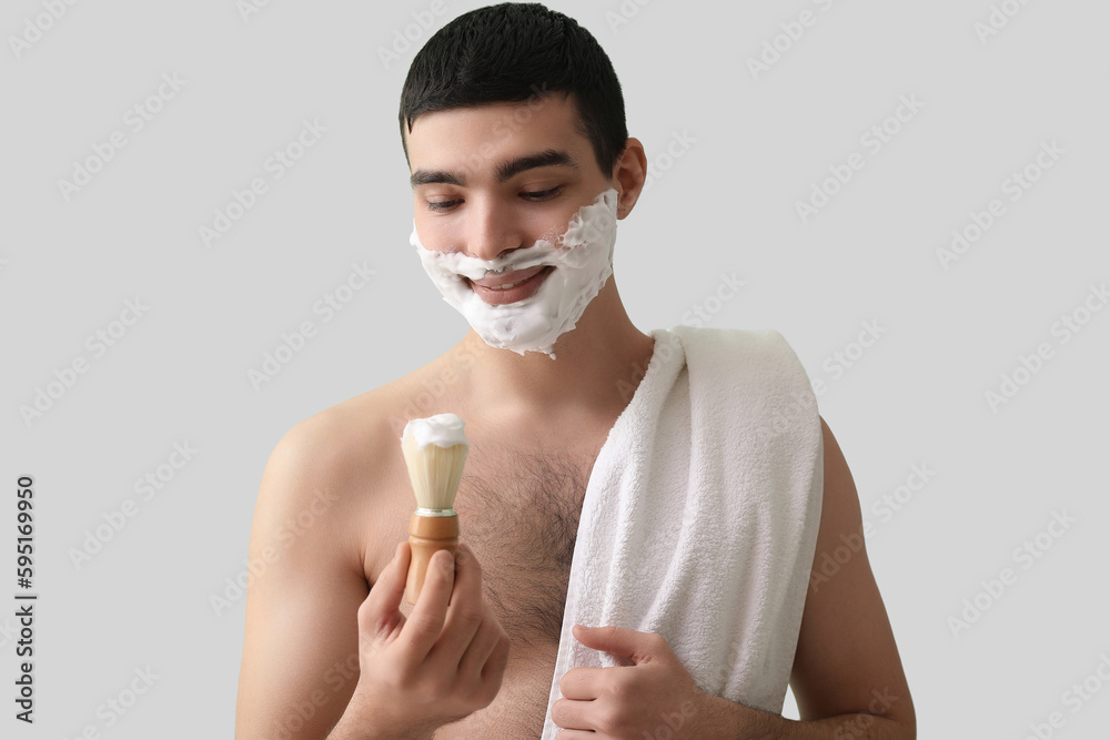 Young man shaving against green background