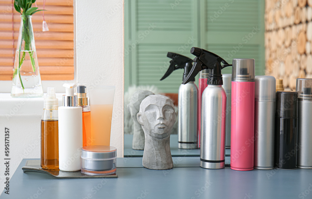 Bottle of spray and hair care products on table in beauty salon