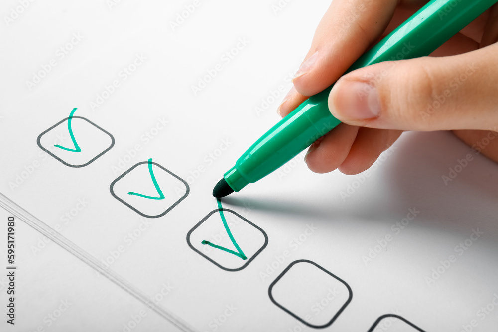 Woman marking on checklist box, closeup