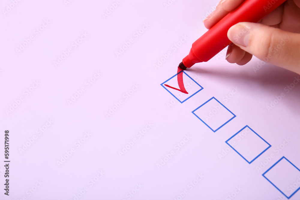 Woman marking on checklist box, closeup