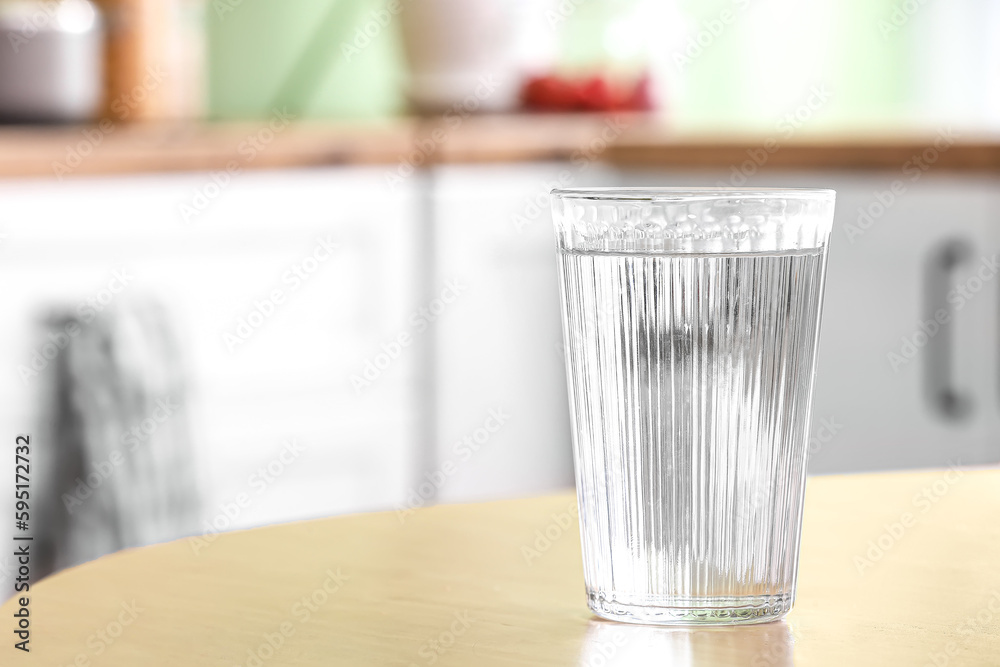 Glass of water on wooden table in kitchen, closeup