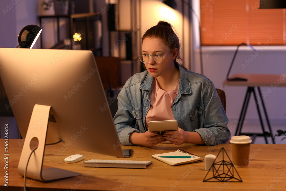 Female programmer working with computer in office at night