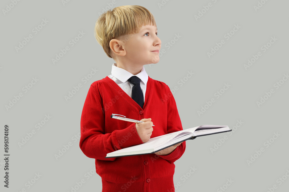 Funny little businessman writing in notebook on grey background