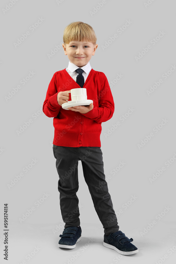 Funny little businessman with cup of coffee on grey background