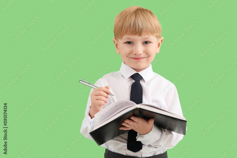 Funny little businessman writing in notebook on green background