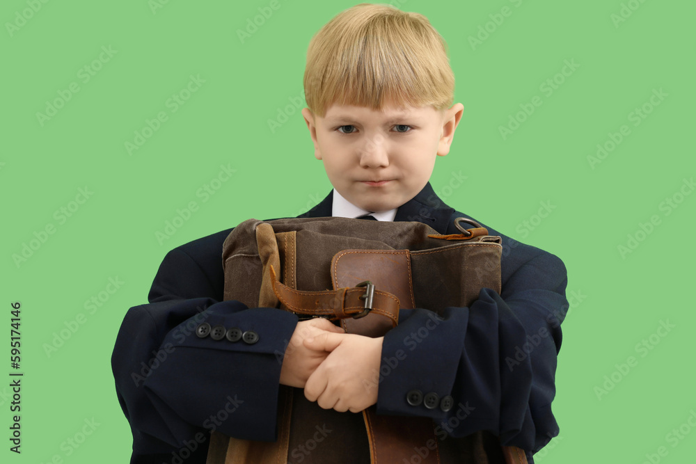 Funny little businessman in big jacket with briefcase on green background