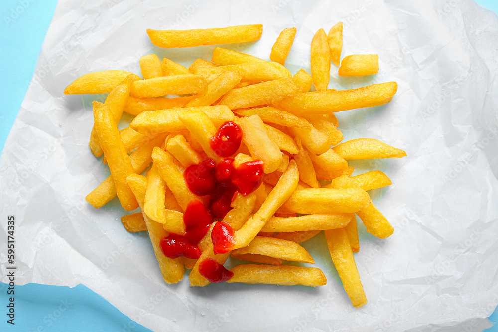 Baking paper with tasty french fries and ketchup on color background, closeup