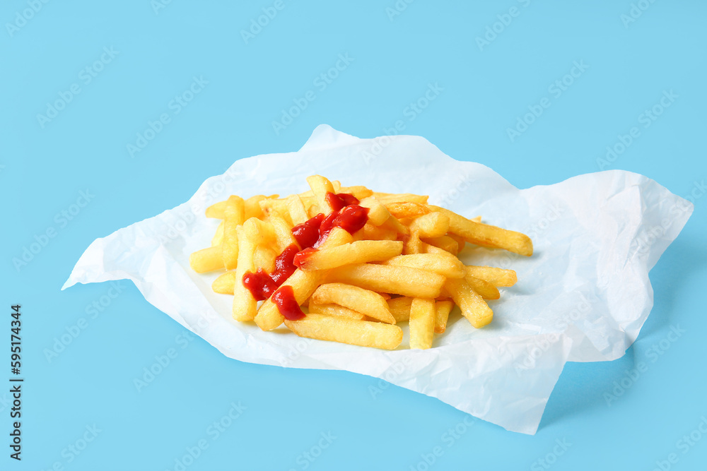 Baking paper with tasty french fries and ketchup on color background