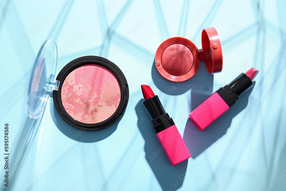 Beautiful lipsticks and blush on color background