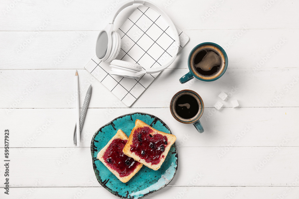 Cups of coffee with toasts, headphones and stationery on white wooden background