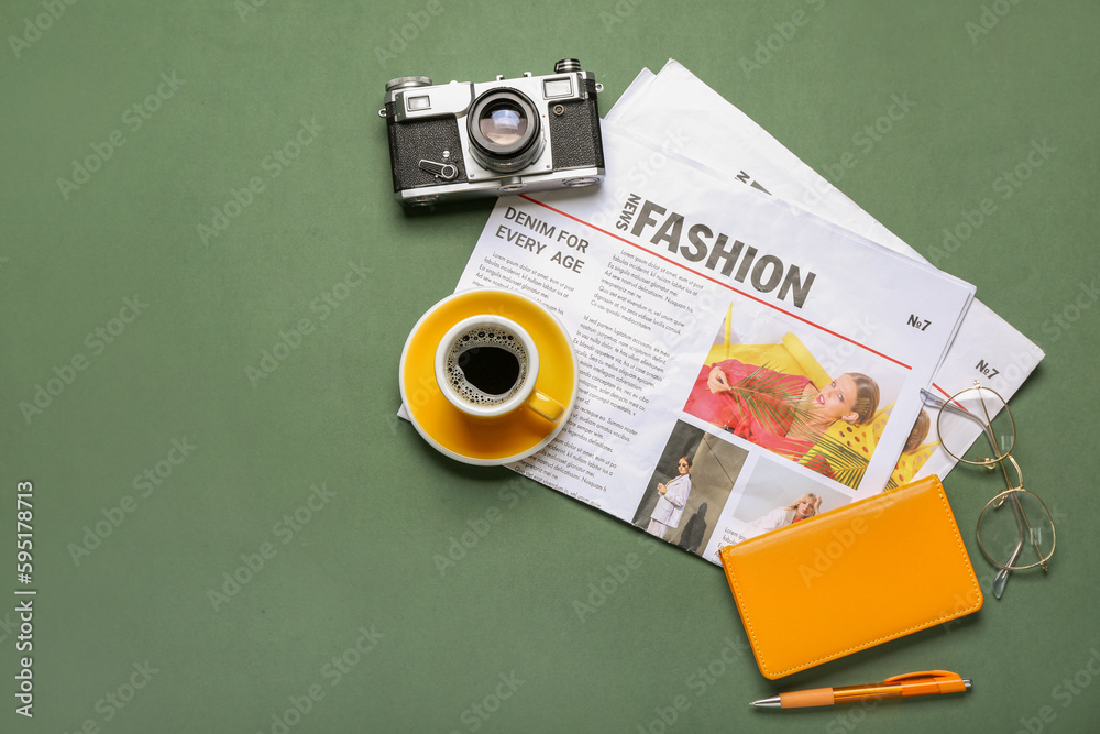 Newspapers with cup of coffee, photo camera, eyeglasses and notebook on green background