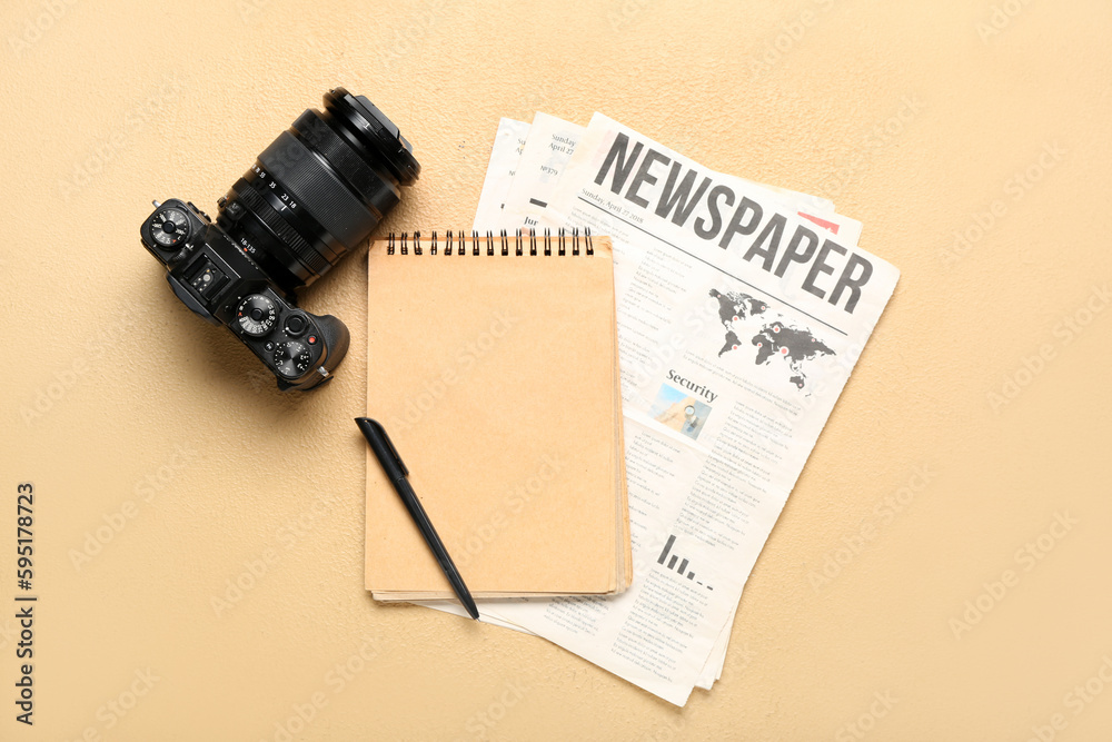 Newspapers with notebook and photo camera on beige background