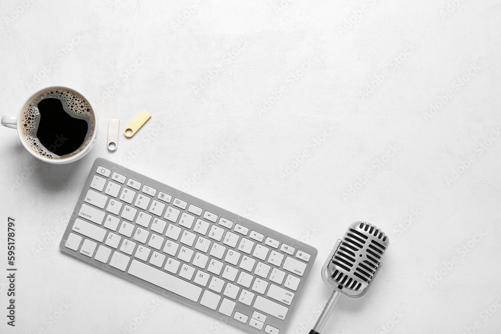 Computer keyboard with USB flash drives, microphone and cup of coffee on white background