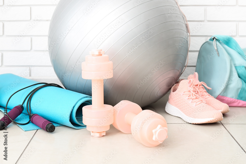 Sports equipment with sneakers near white brick wall, closeup