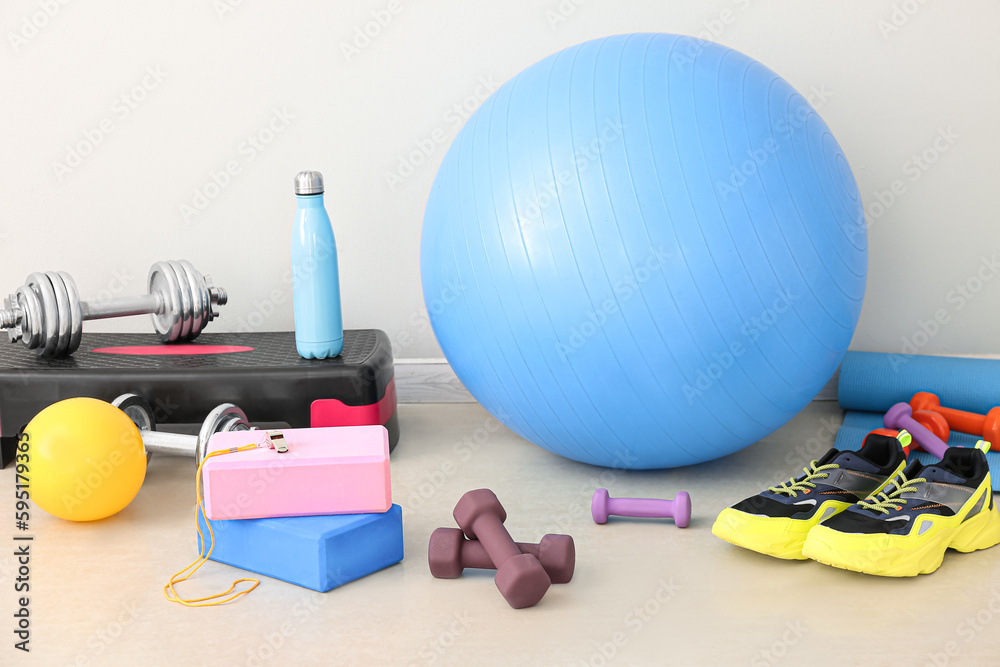 Sports equipment with sneakers near light wall in gym