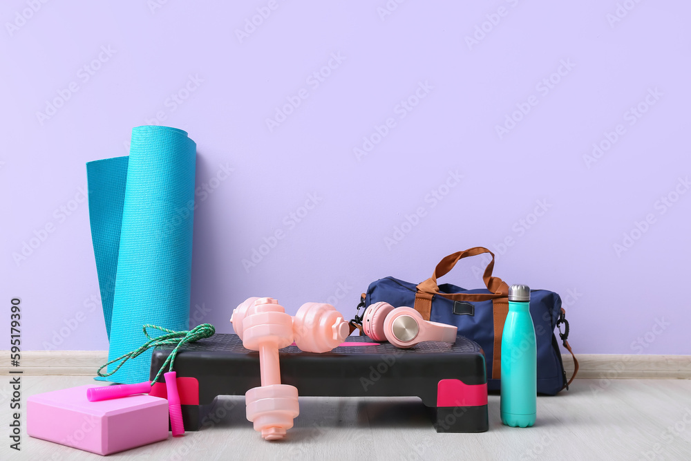 Sports equipment with headphones near lilac wall in gym