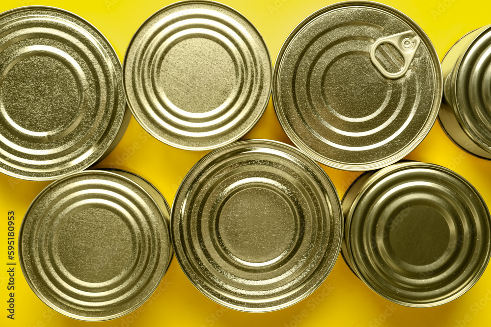 Assortment of tin cans with fish on yellow background, closeup