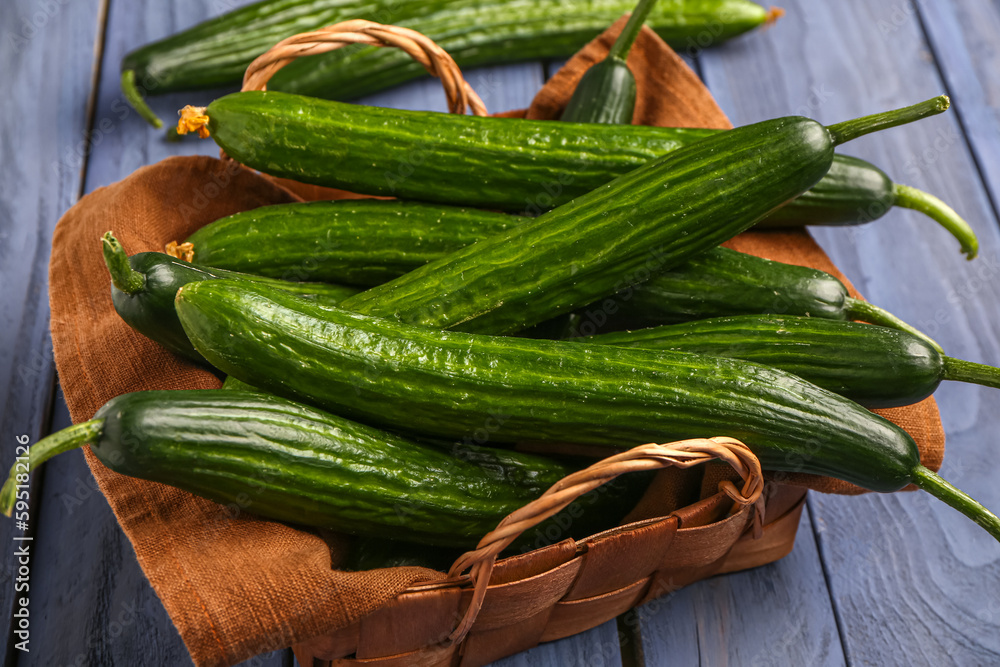 Basket with fresh cucumbers on grey wooden background